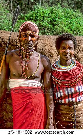 Stock Image - Maasai tribe people couple in costume traditional dress in jungles near hut near Kenya Africa. Fotosearch