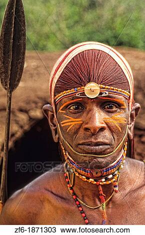 Stock Image - Maasai tribe people in costume traditional dress in jungles in front of hut near Kenya Africa. Fotosearch