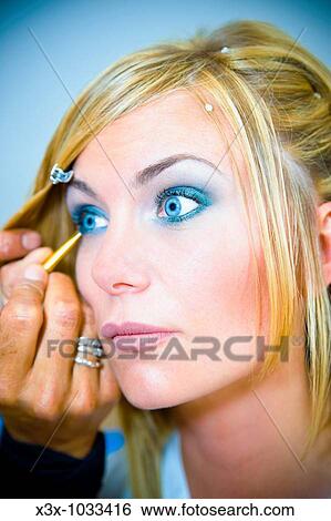 Make-up artist applying blue eye liner on a woman View Large Photo Image Stock Photograph - Make-up artist applying blue eye liner on a woman. Fotosearch