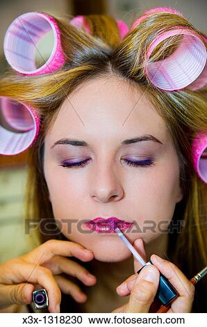 Make-up artist applying lip gloss on a woman with curlers in her hair View Large Photo Image Stock Image - Make-up artist applying lip gloss on a woman with curlers in her hair. Fotosearch
