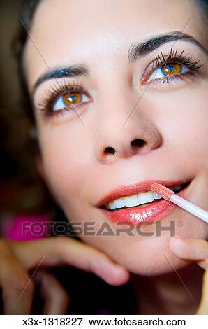 Make up artist applying lip gloss on a woman smiling View Large Photo Image Stock Photo - Make up artist applying lip gloss on a woman smiling. Fotosearch
