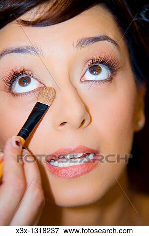 Makeup artist applying eyeshadow on a young woman with eyes open View Large Photo Image Stock Photo - Makeup artist applying eyeshadow on a young woman with eyes open. Fotosearch