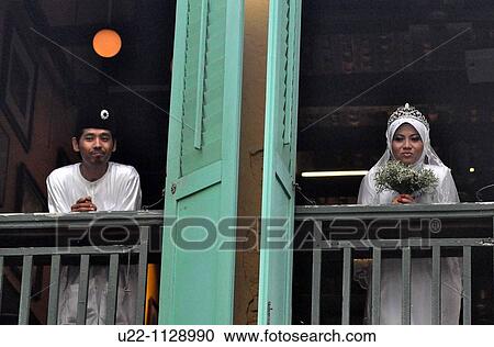 Stock Image - Malacca (Malaysia): Malay newly-weds posing for a photo by the window in Chinatown. Fotosearch