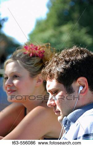 male and female sitting together outdoors- male listening to music View Large Photo Image Stock Photograph - male and female sitting together outdoors- male listening to music. Fotosearch