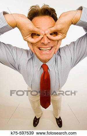 Stock Photo - male, caucasian, fingers, hands, tie, gestures, eyes, smiling, comedic, humor. Fotosearch