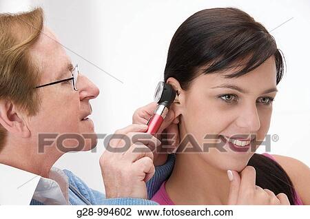 male doctor examining ear of a woman patient with otoscope View Large Photo Image Stock Image - male doctor examining ear of a woman patient with otoscope. Fotosearch