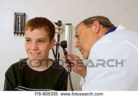 Male doctor, using an otoscope, examining the ear of a teen age boy, during a medical exam in doctor's office View Large Photo Image Stock Photography - Male doctor, using an otoscope, examining the ear of a teen age boy, during a medical exam in doctor's office. Fotosearch