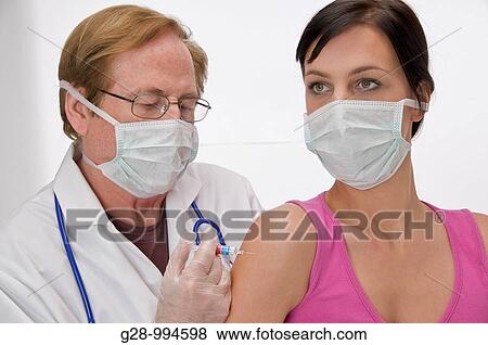 male doctor with mask vaccinating or giving an injection to young woman patient with mask too View Large Photo Image Stock Photo - male doctor with mask vaccinating or giving an injection to young woman patient with mask too. Fotosearch