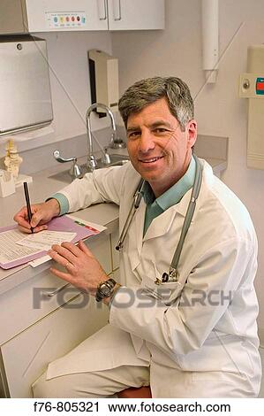 Male doctor working on patient chart in exam room of medical office View Large Photo Image Stock Image - Male doctor working on patient chart in exam room of medical office. Fotosearch
