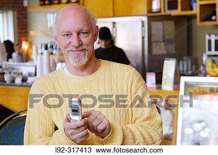 Male in yellow sweater cell phone at cafe View Large Photo Image Stock Image - Male in yellow sweater cell phone at cafe. Fotosearch