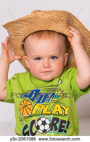 Male toddler child, 18 months old, caucasian ethnicity, is grabbing a straw cowboy hat he's wearing, which is way too large for him. Looking friendly at the camera. View Large Photo Image Stock Photograph - Male toddler child, 18 months old, caucasian ethnicity, is grabbing a straw cowboy hat he's wearing, which is way too large for him. Looking friendly at the camera.. Fotosearch