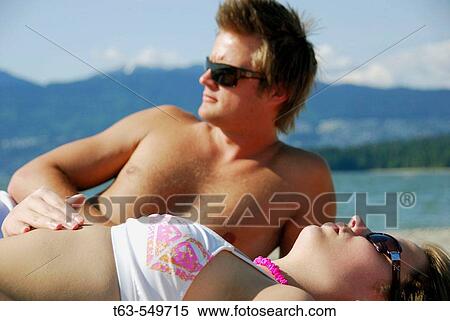 man 23 yrs, woman 20 yrs, on beach suntanning together View Large Photo Image Stock Photography - man 23 yrs, woman 20 yrs, on beach suntanning together. Fotosearch