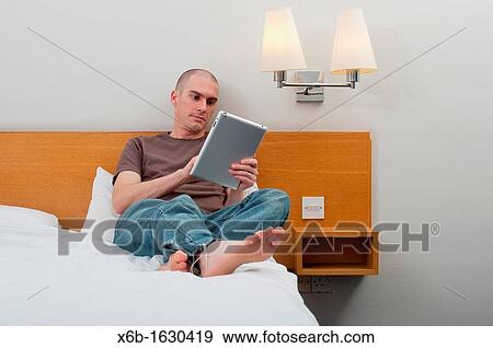Man, 30-40 years, using digital tablet in a hotel room View Large Photo Image Stock Photo - Man, 30-40 years, using digital tablet in a hotel room. Fotosearch