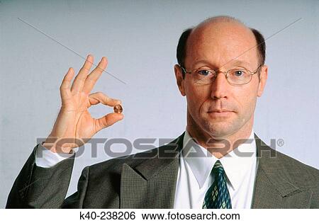 Man, 40-45, in suit, holding coin between fingers View Large Photo Image Stock Photograph - Man, 40-45, in suit, holding coin between fingers. Fotosearch