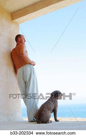 Picture - man and dog admiring view from seaside house. Fotosearch