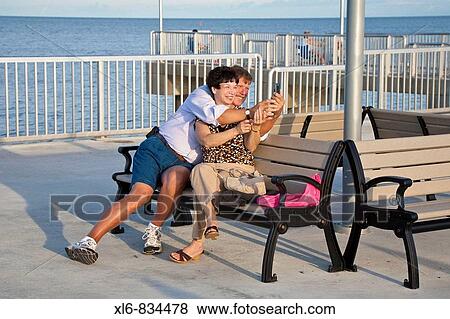 Man and woman couple take photos while sitting on bench on fishing pier at Cedar Key, Florida. View Large Photo Image Stock Photo - Man and woman couple take photos while sitting on bench on fishing pier at Cedar Key, Florida.. Fotosearch
