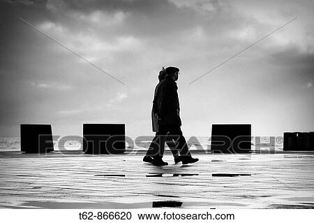 Man and woman walking in winter by the sea View Large Photo Image Stock Image - Man and woman walking in winter by the sea. Fotosearch
