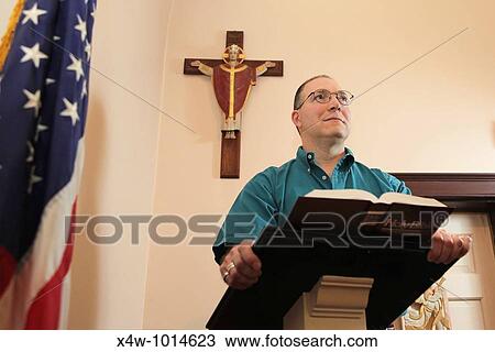 Stock Image - Man at church pulpit preaching to congregation with American Flag and crucifix. Fotosearch