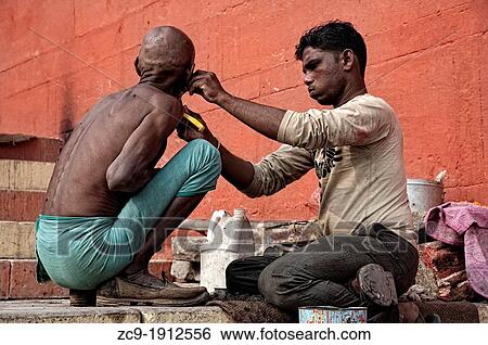 Stock Photograph - Man being shaved by a barber at a ghat Varanasi, Benares, Uttar Pradesh, India. Fotosearch