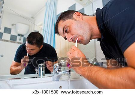 Man brushing teeth in front of the mirror View Large Photo Image Stock Image - Man brushing teeth in front of the mirror. Fotosearch