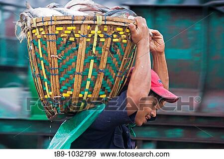 man caring basket of fish in the morning market View Large Photo Image Stock Photo - man caring basket of fish in the morning market. Fotosearch