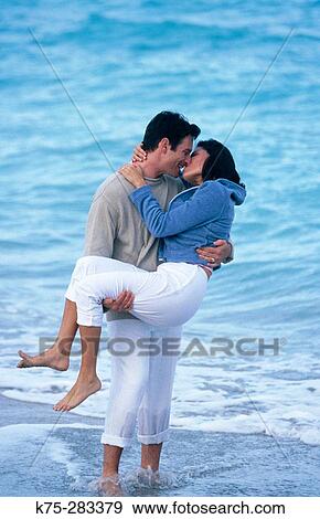 Stock Photo - Man carrying and kissing his love. Fotosearch