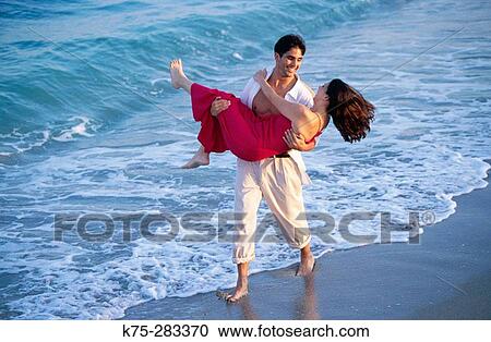 Man carrying his girlfriend on the beach View Large Photo Image Stock Image - Man carrying his girlfriend on the beach. Fotosearch