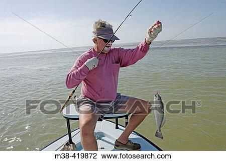 Stock Image - Man catching a Red Fish in Islamorada, Florida. December 2004.. Fotosearch
