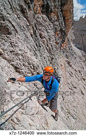 Stock Image - Man climbing the Giovanni Lipella via ferrata on Tofana De Rozes in the Dolomite Mountains near the city of Cortina in northern Italy. Fotosearch