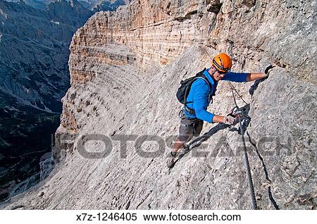 Man climbing the Giovanni Lipella via ferrata on Tofana De Rozes in the Dolomite Mountains near the city of Cortina in northern Italy View Large Photo Image Stock Photography - Man climbing the Giovanni Lipella via ferrata on Tofana De Rozes in the Dolomite Mountains near the city of Cortina in northern Italy. Fotosearch