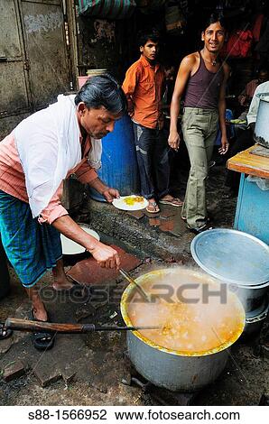 Stock Image - Man cooking beans curry in Old Delhi. Fotosearch