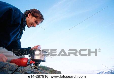 Stock Photograph - Man cooking meal on stove. Chugach State Park. Southcentral Alaska. Fotosearch