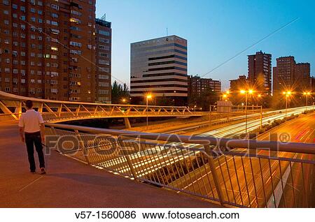 Stock Photograph - Man crossing La Paloma bridge over M-30 motorway, night view. Madrid, Spain.. Fotosearch