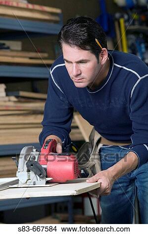 Man cutting wood with a circular saw. View Large Photo Image Picture - Man cutting wood with a circular saw.. Fotosearch