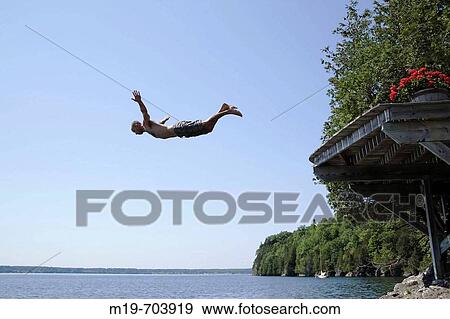 Stock Photo - Man diving into a lake from a deck. Fotosearch