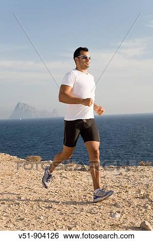 Man doing jogging in a cliff by the sea in Ibiza View Large Photo Image Stock Photograph - Man doing jogging in a cliff by the sea in Ibiza. Fotosearch