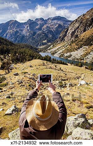 Stock Image - Man doing photo. `Estany Llong?,Llong lake, from the vicinity of Portarro de Espot, Aig? estortes i Estany de Sant Maurici National Park, Pyrenees, Lleida province, Catalonia, Spain.. Fotosearch