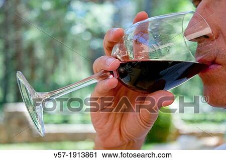 Stock Image - Man drinking a glass of red wine. Close view.. Fotosearch