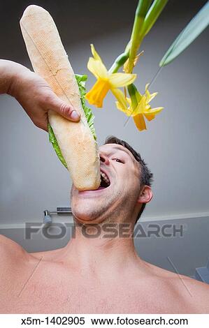 Man eating a large baguette in his kitchen View Large Photo Image Stock Photography - Man eating a large baguette in his kitchen. Fotosearch