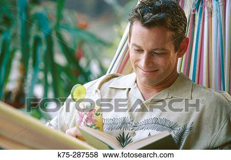 Stock Photo - man enjoying a tropical drink and a book. Fotosearch