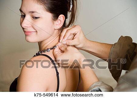 Picture - Man fastening woman's necklace. Fotosearch