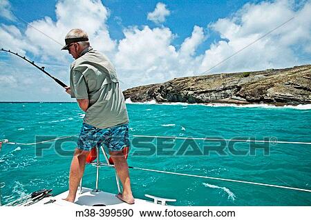 Man fishing off the back of a catamaran while sailing in Antigua View Large Photo Image Stock Image - Man fishing off the back of a catamaran while sailing in Antigua. Fotosearch