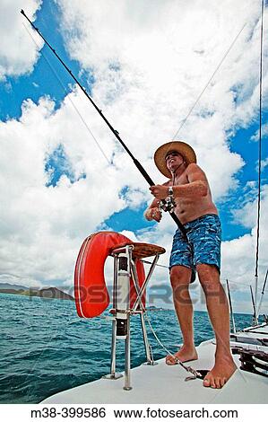 Man fishing off the back of a catamaran while sailing in Antigua View Large Photo Image Stock Photograph - Man fishing off the back of a catamaran while sailing in Antigua. Fotosearch