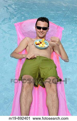 Man floating in a pool eating fruit. View Large Photo Image Stock Image - Man floating in a pool eating fruit.. Fotosearch