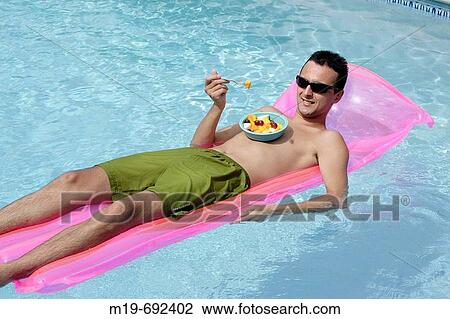 Man floating in a pool eating fruit View Large Photo Image Stock Image - Man floating in a pool eating fruit. Fotosearch