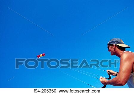 Man flying a kite with a blue sky View Large Photo Image Stock Image - Man flying a kite with a blue sky. Fotosearch