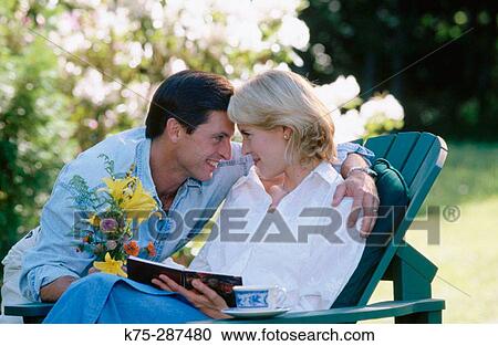 man gives his love a bouquet of flowers while she's reading View Large Photo Image Stock Image - man gives his love a bouquet of flowers while she's reading. Fotosearch