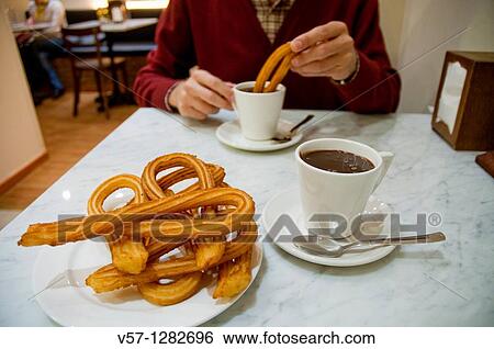 Stock Photograph - Man having chocolate with churros. Close view.. Fotosearch