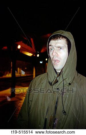 Man hearing the news that the train he is waiting for on a snowy winter night is delayed. View Large Photo Image Picture - Man hearing the news that the train he is waiting for on a snowy winter night is delayed.. Fotosearch