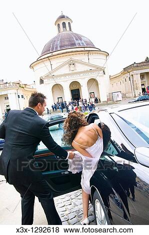 Stock Photo - Man helping woman enter the car. Fotosearch